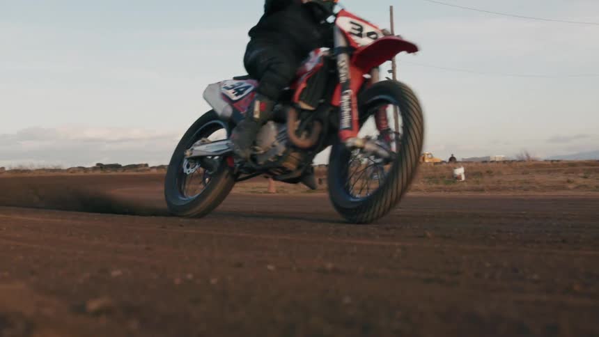 Dirt bike racing along a dirt track spews earth into the air