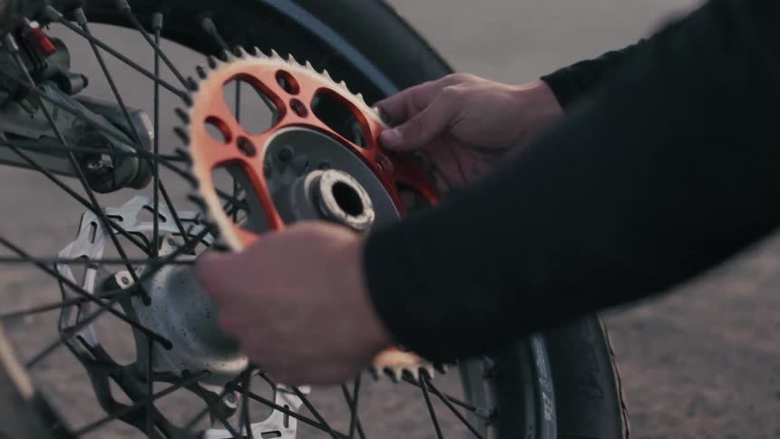 A man is replacing the gears on a motorcycle wheel