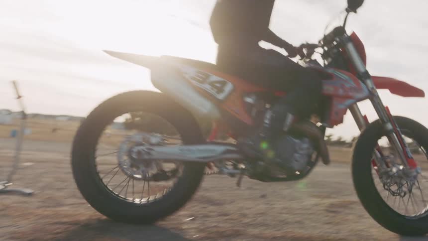 A person riding a racing motorcycle onto a race track fully kitted with a helmet and gear on a sunny day