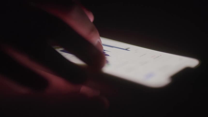 A persons finger operates a mobile device placed on a surface