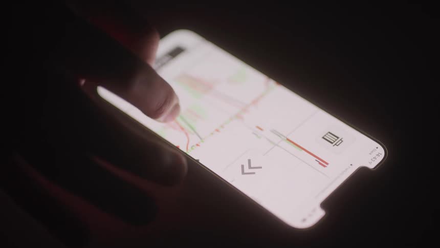 A person using a cellphone to view binary options charts