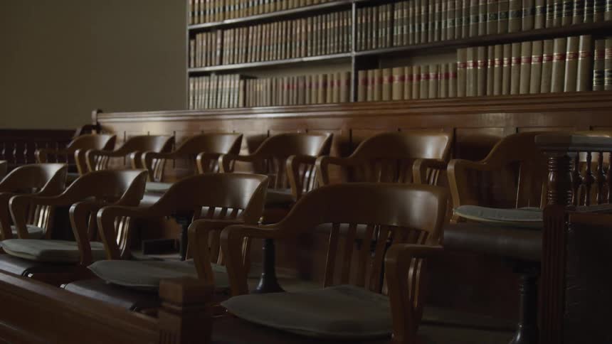 Empty jury box stands next to shelves full of legal books in the courtroom