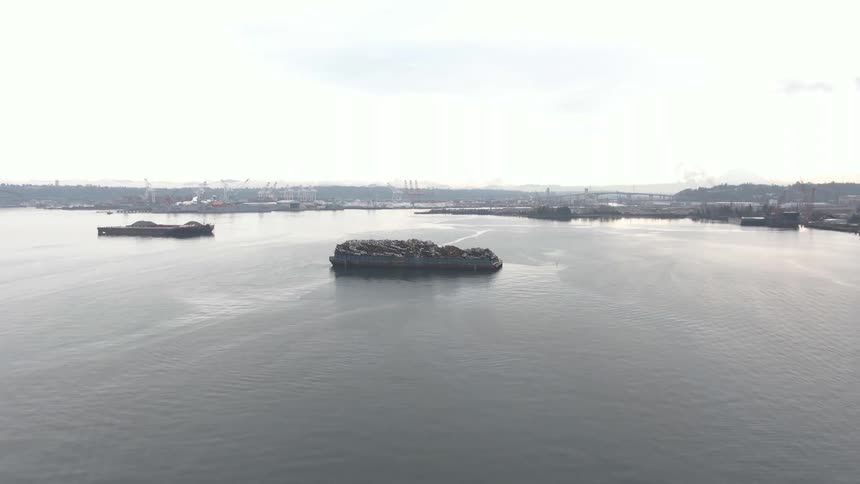 Barges are docked by the factory on the shore