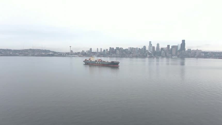 Aerial view of a cargo ship and a metropolis in the background