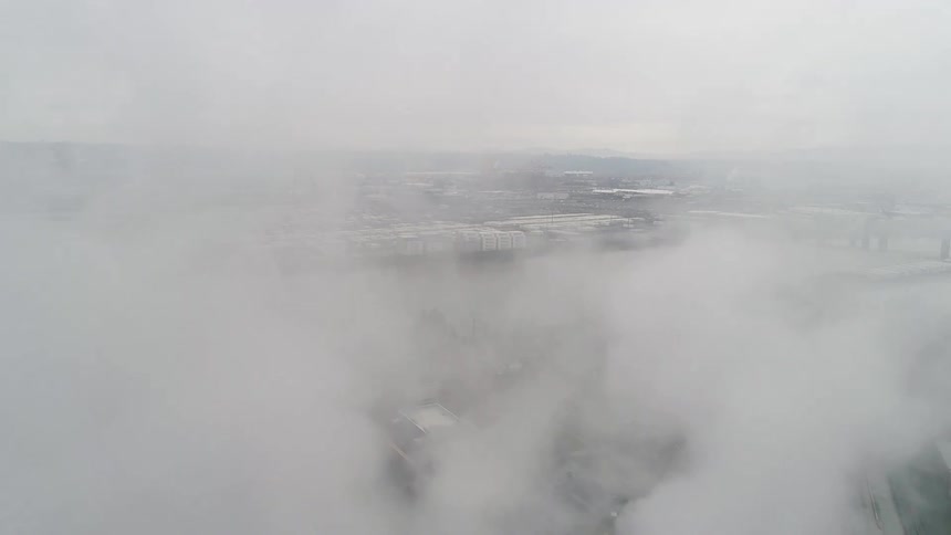 Low lying clouds obscure the docks and the riverside industrial parks