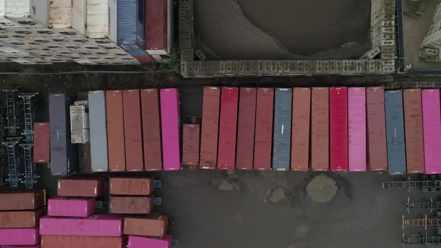 Aerial view of colorful shipping containers neatly lined up in an industrial freight yard