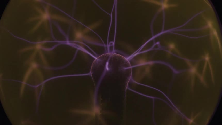 Purple and orange tendrils of light dance and flicker from a central electrode inside a plasma globe in a stationary closeup shot