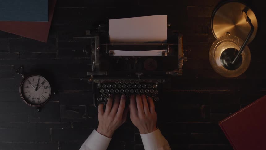 A person types using a typewriter on a tabletop