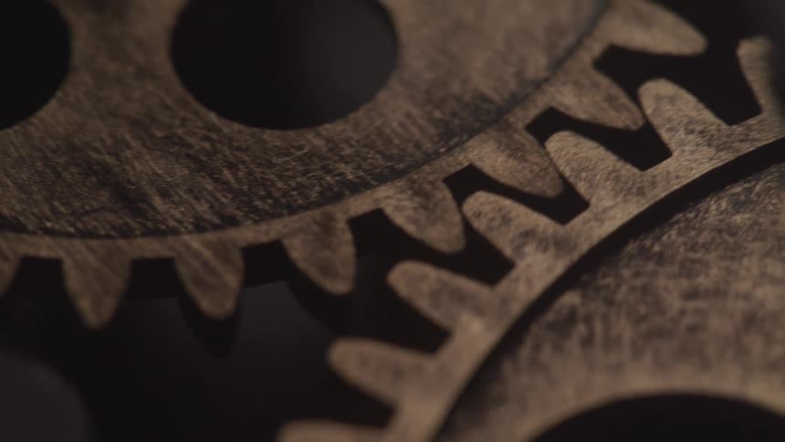 A closeup shows interlocking metallic gears spinning with visible texture and wear