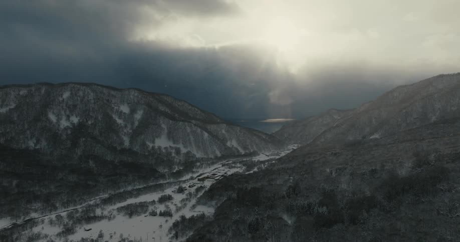 The sun shines through the heavy clouds on the mountains