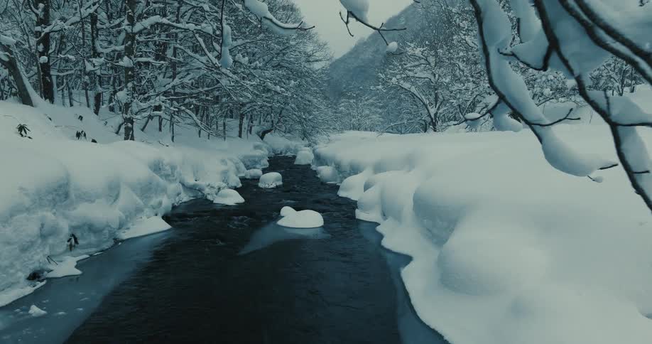 A river with lots of snow around and frozen trees