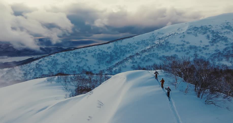 3 people walking on a snowcovered mountain