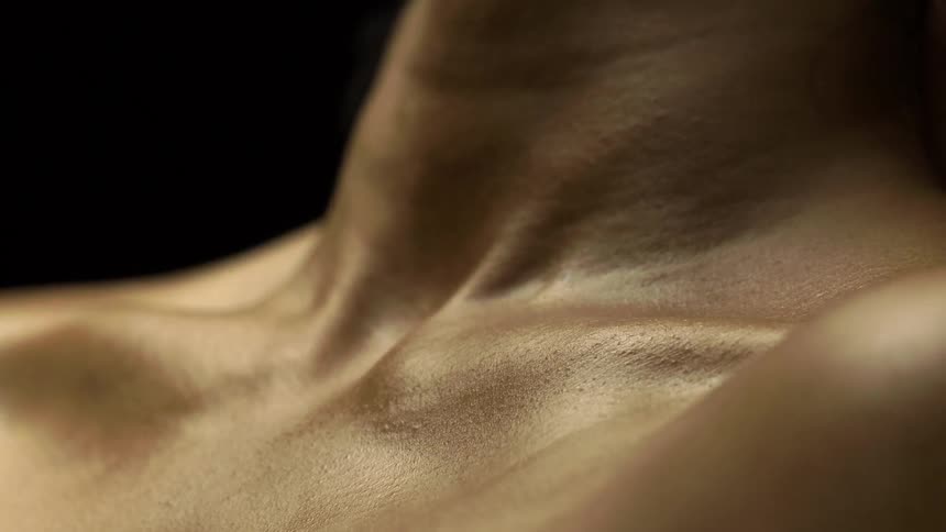 Closeup of a shirtless persons torso against a black background
