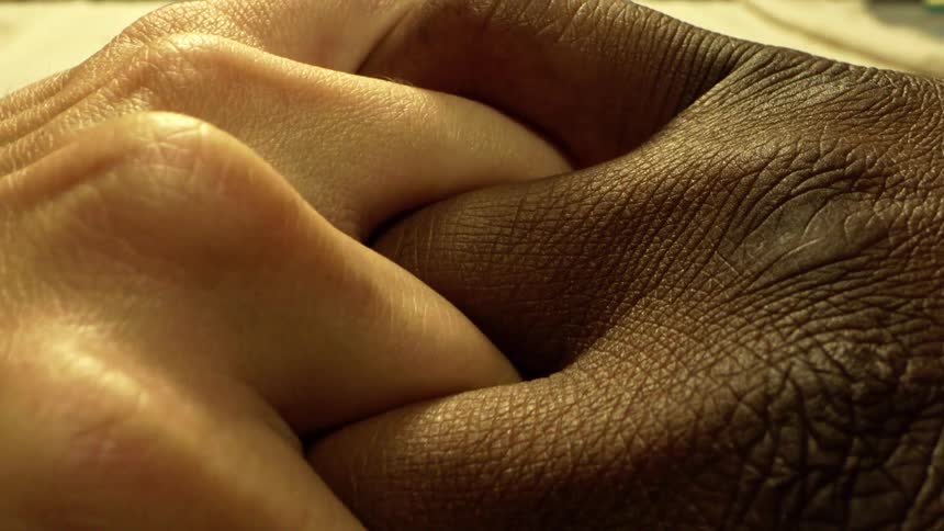 Two hands are intertwined closely together