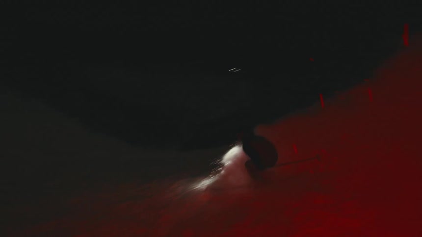 A skier speeds through a dark foggy area with a headlamp shining brightly with a red glow on the snowcovered ground