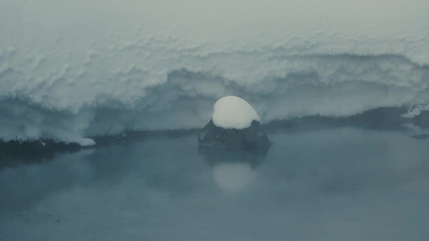 A white radar dome stands alone on icy land surrounded by calm arctic waters
