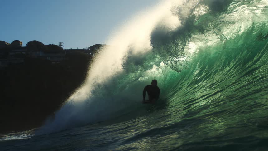 A man rides his surfboard in a large wave
