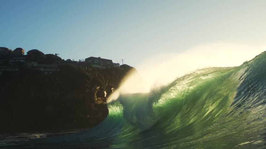 A large wave moves by the cliff