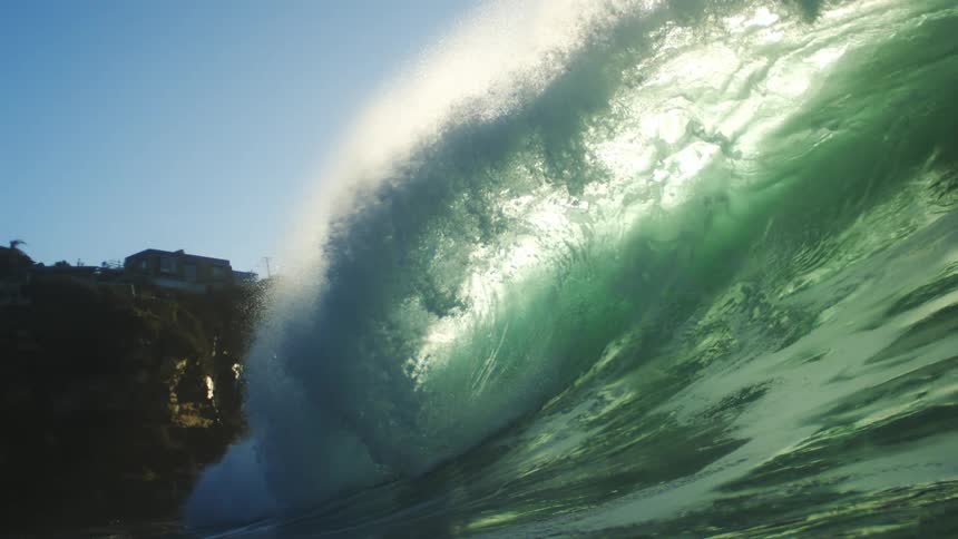 A huge wave crashes against the mountain shore