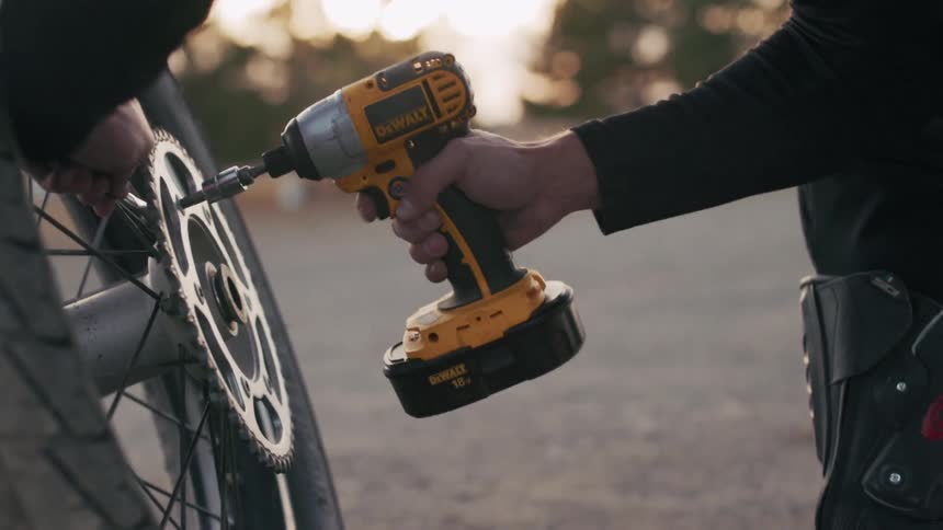 Hand using a screwdriver to screw on a motorcycle wheel