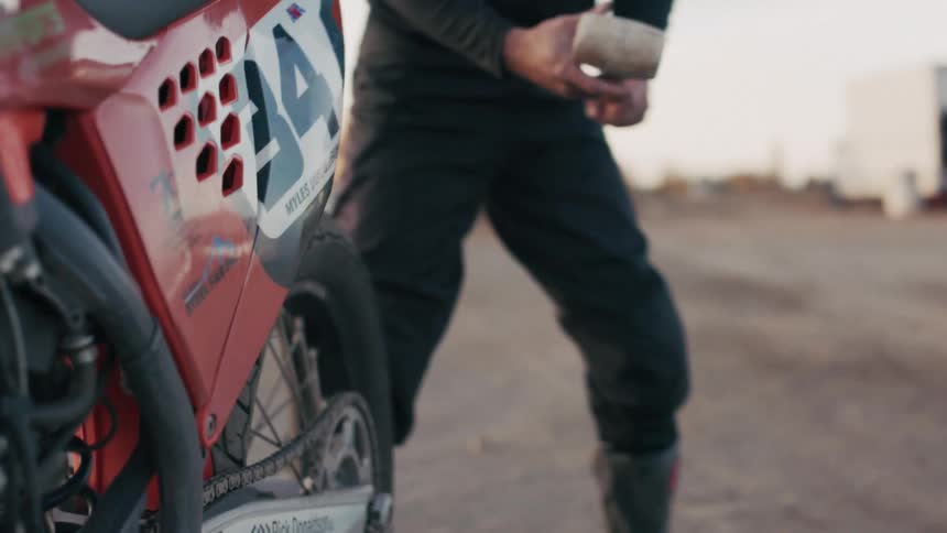 Man holding a sledgehammer next to a motocross motorcycle