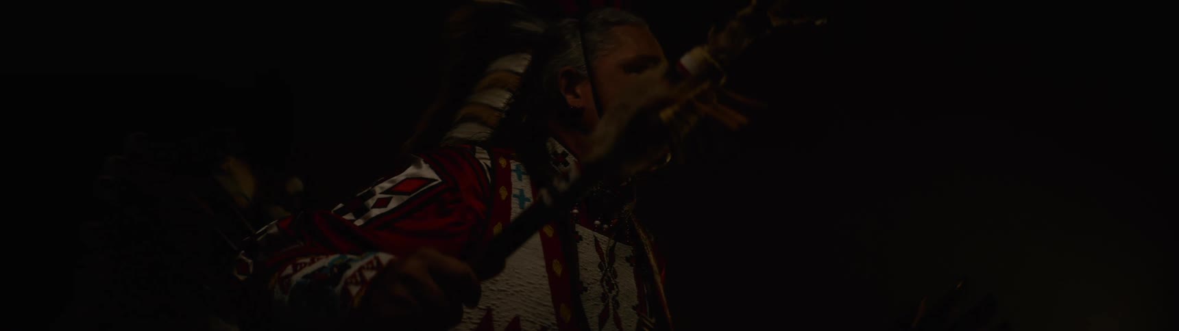 Man in traditional indigenous costume in a lowlight environment