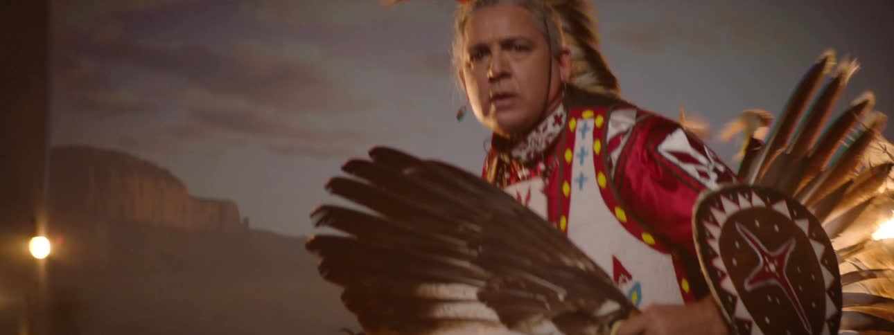 An american native man dressed in traditional attire dancing on a stage