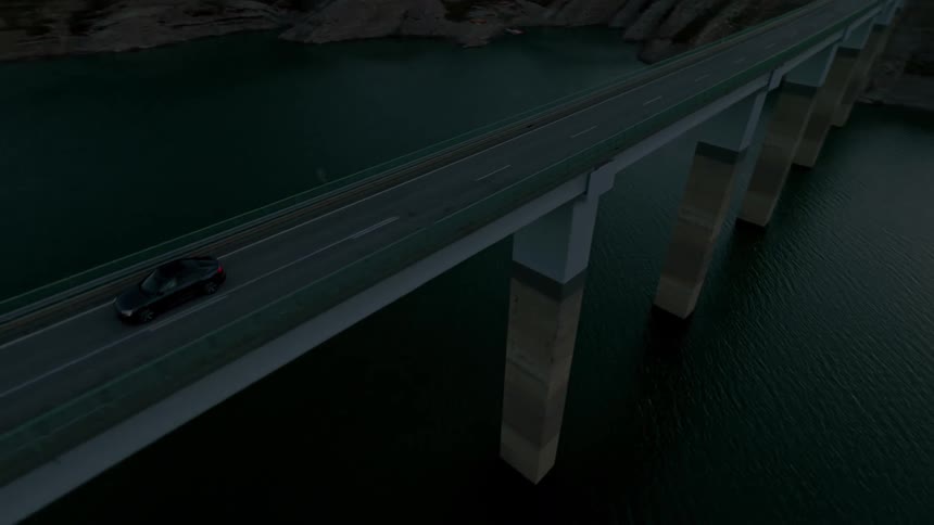 A vehicle drives across a high bridge over a lake at dusk surrounded by forested mountains