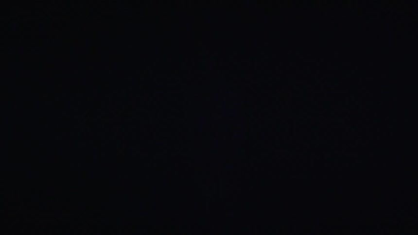 A woman models clothing in a dark room with blue lights