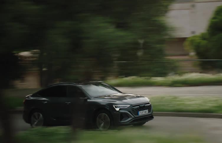 The car travels down the road by the building