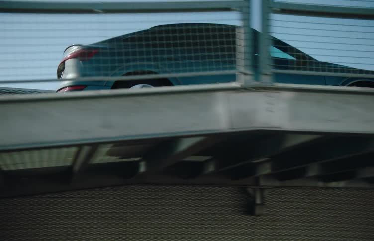 Car rides climbs a metal bridge in a city at daytime