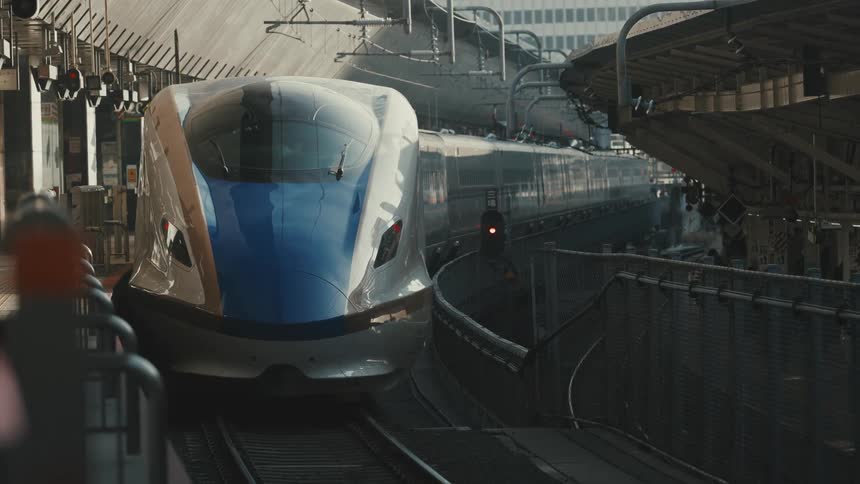 Train waits on the tracks between city structures during the daytime