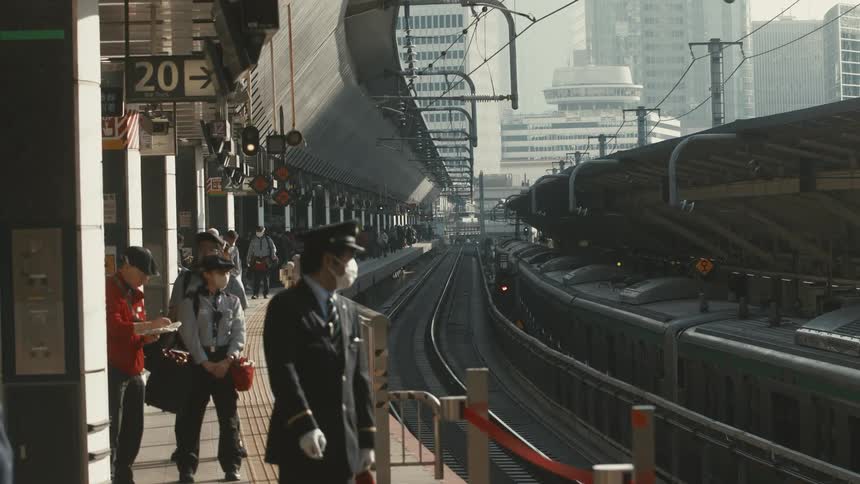 Workers and passengers wait for the train