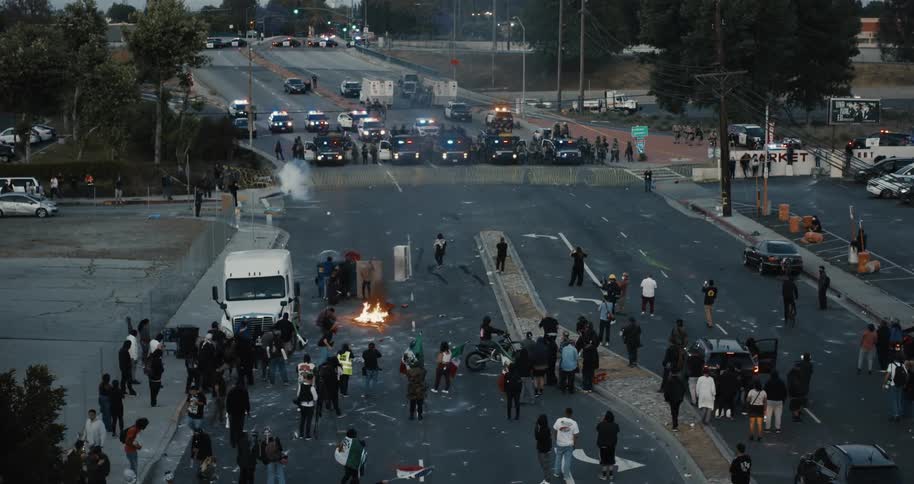 Protesters face off against police on a blocked city street with fire and debris