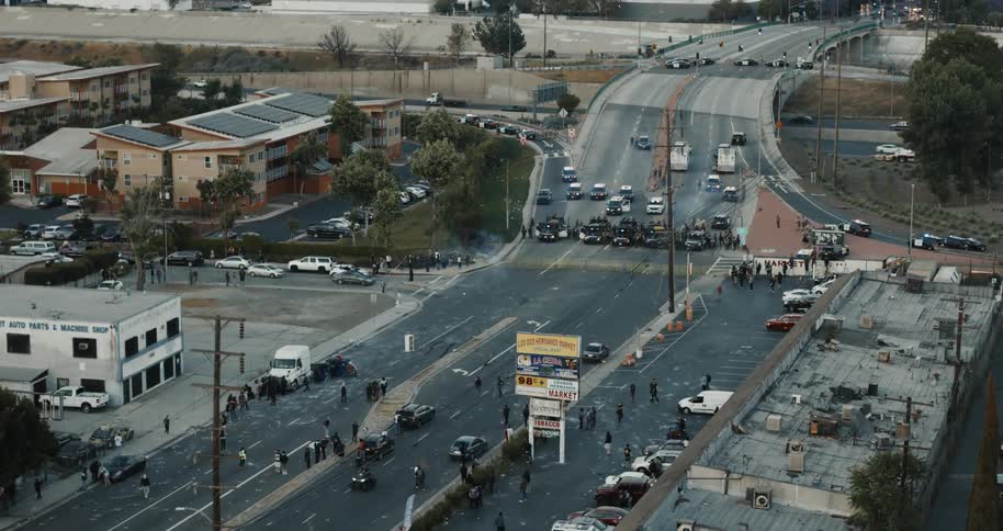 Crowds and vehicles gather at a police roadblock on a major city street