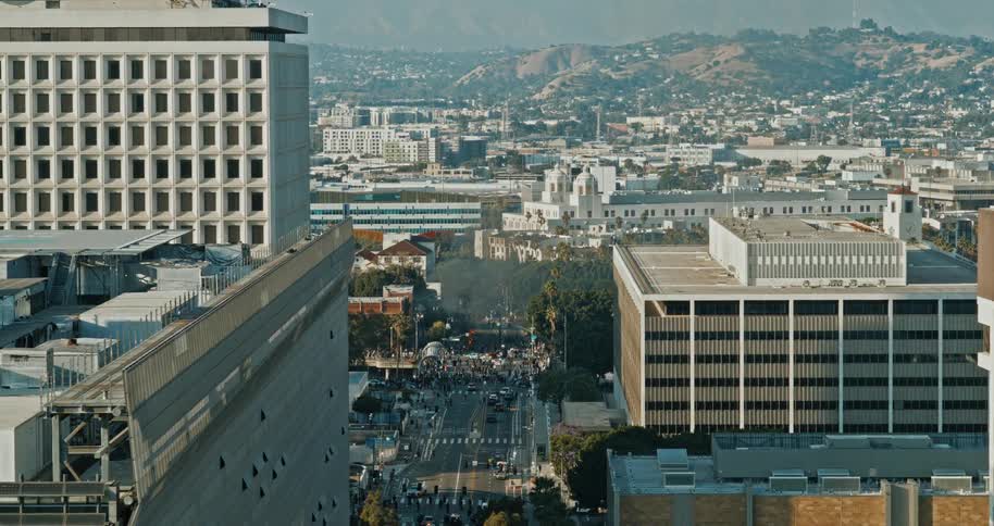 Aerial view of a downtown Los Angeles with protesters and burning Waymo cars in the background