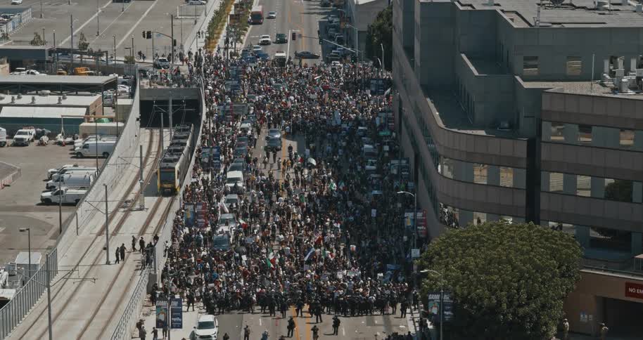 A crowd marches down a city street in a protest