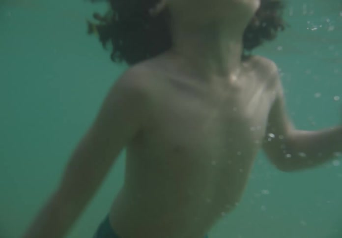 Curly haired boy swimming in the ocean