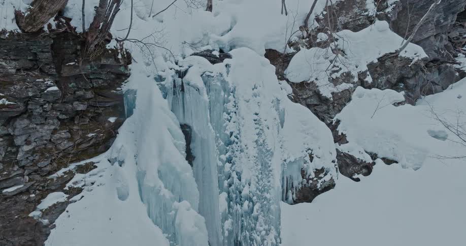 A frozen waterfall cascades down a snowcovered rocky cliff in a winter landscape