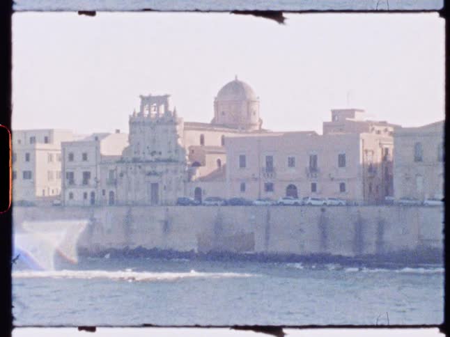 A historic seaside city skyline with a prominent dome viewed from across the water