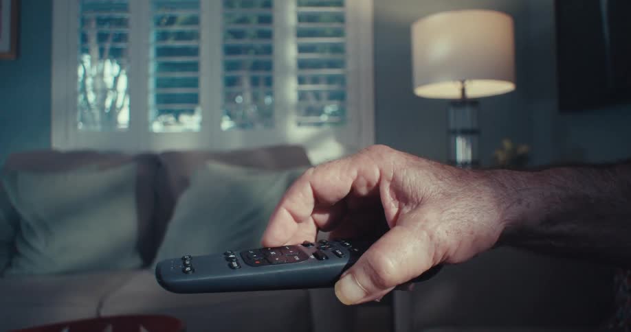 A outstretched hand pointing a tv remote control