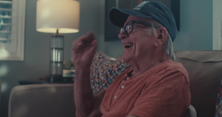 The man is watching tv and laughing at home
