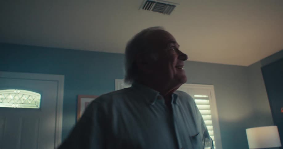 An elderly man dances in his living room at midday