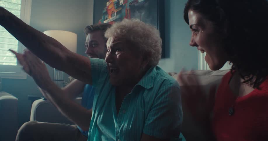 Elderly woman and her family cheer while watching television at home during the daytime