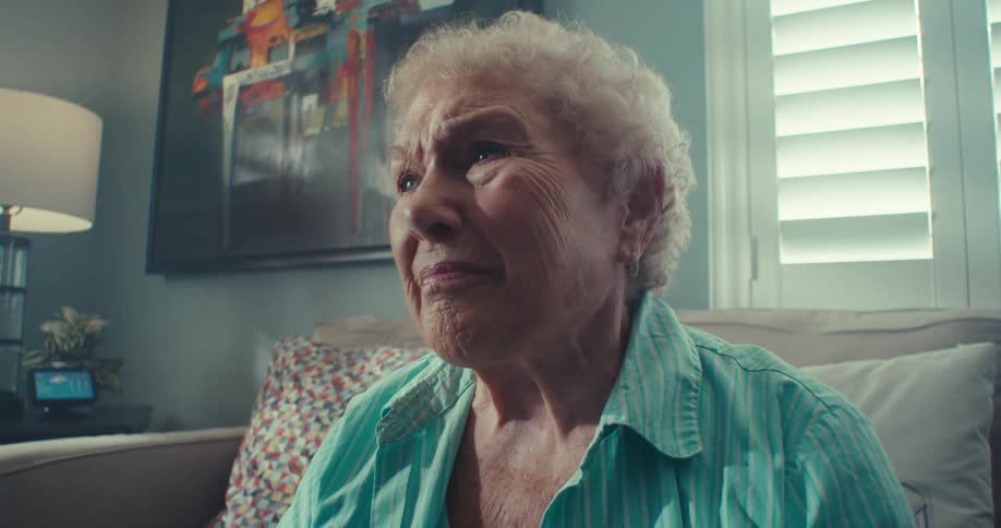 An elderly woman seated on the couch indoor at daytime