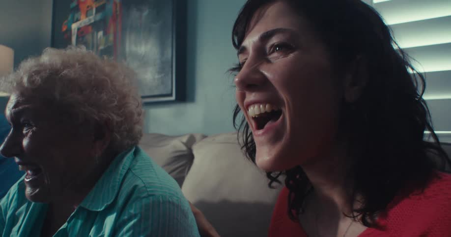 Three people are laughing while watching television