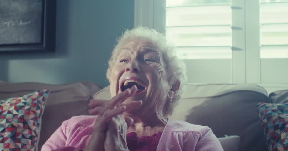 A woman is sitting on a couch and laughing at something