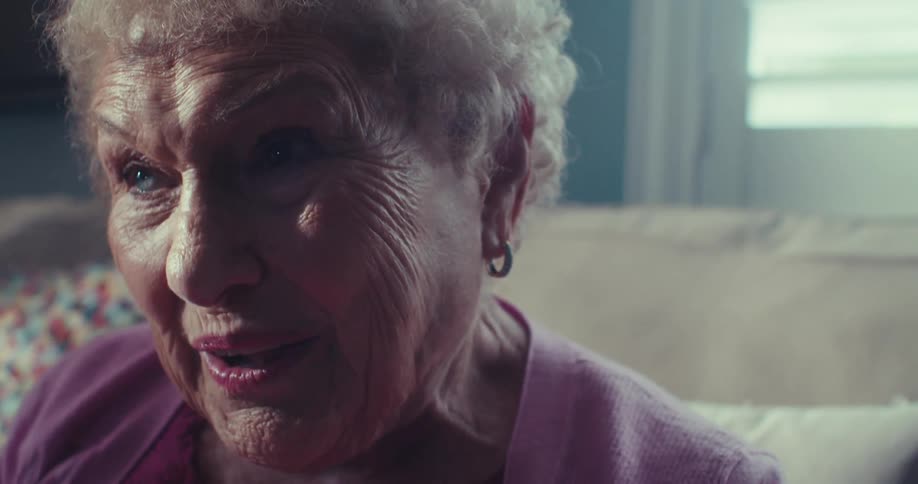 An elderly woman smiles as she leans for while talking