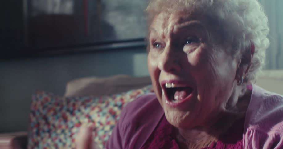 The woman cheers and claps her hands on the couch