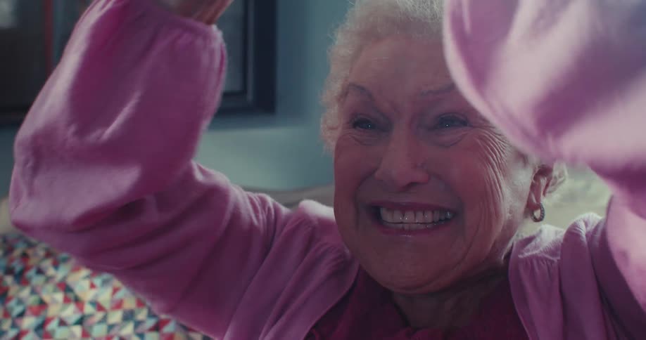 Elderly lady sitting on sofa in living room and vibrating happily